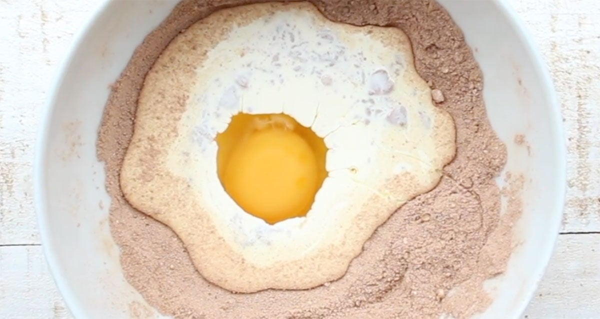 Adding cream and egg to the dry ingredients in a bowl.