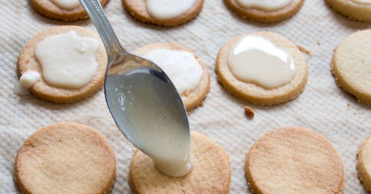 Adding the glaze onto the cookies with a spoon.