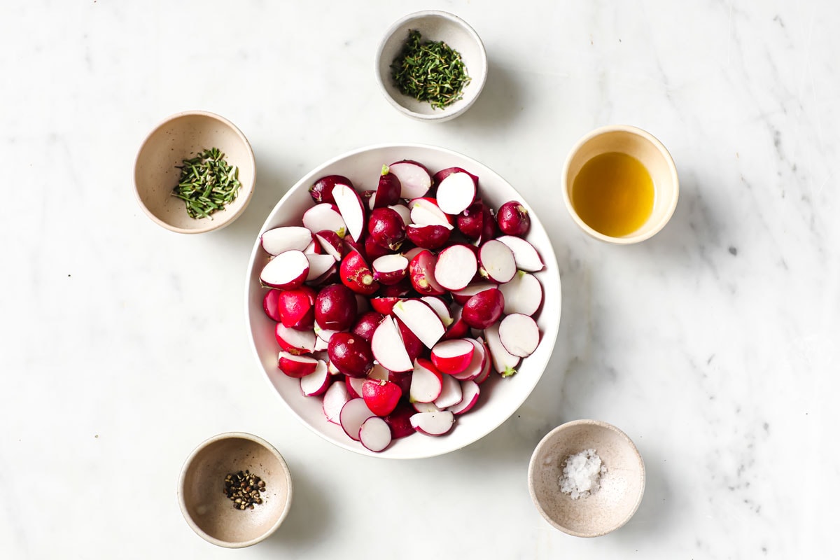Radishes, oil and seasonings measured into bowls.