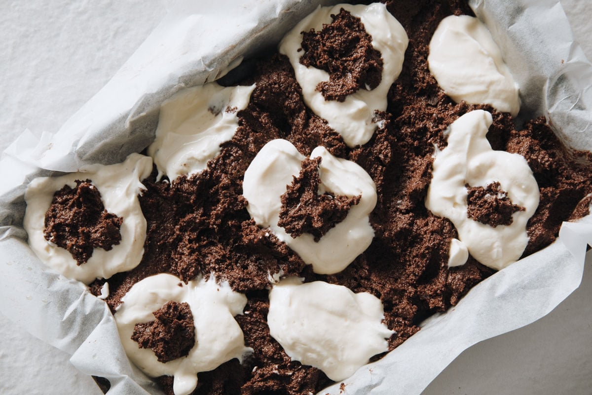 Brownie and cheesecake batter in a pan.