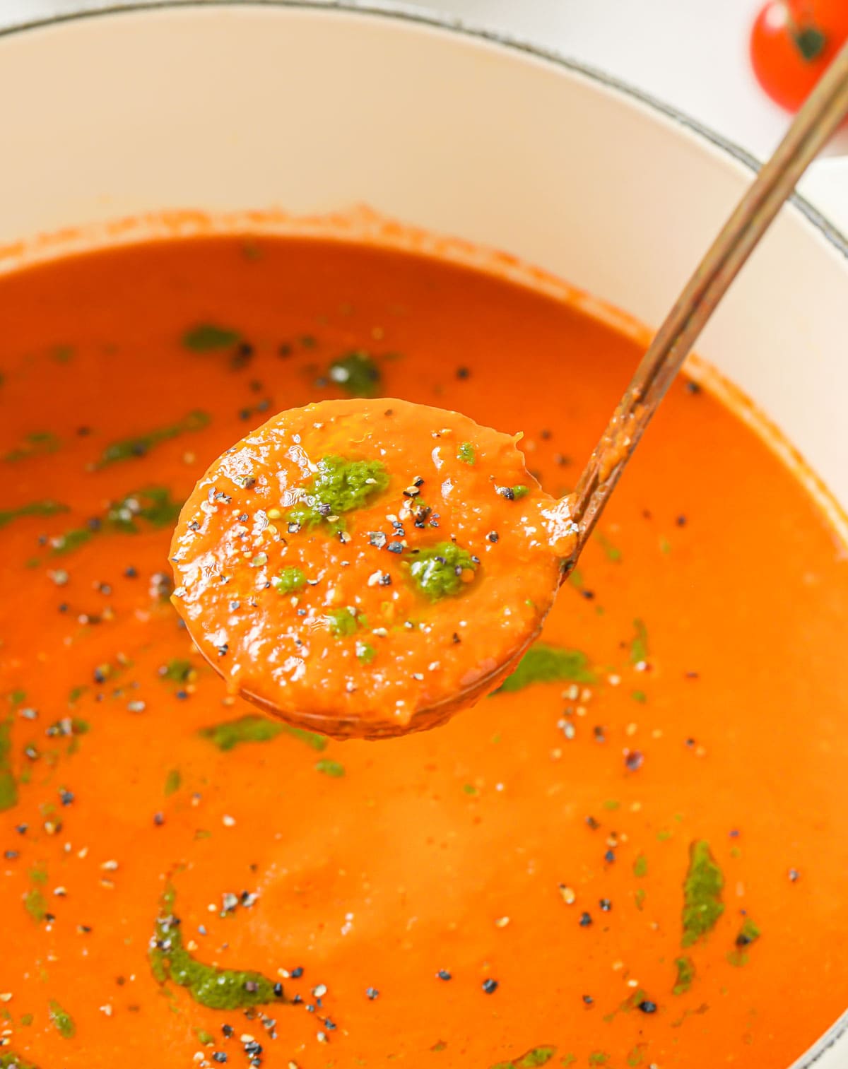 A ladle with tomato soup.
