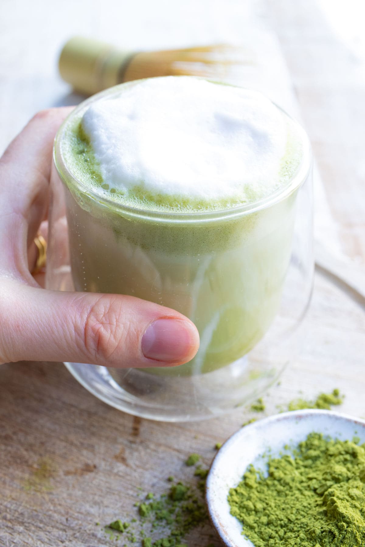 Hand taking a cup with matcha latte.
