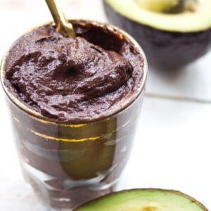 Chocolate avocado pudding in a glass with a spoon.