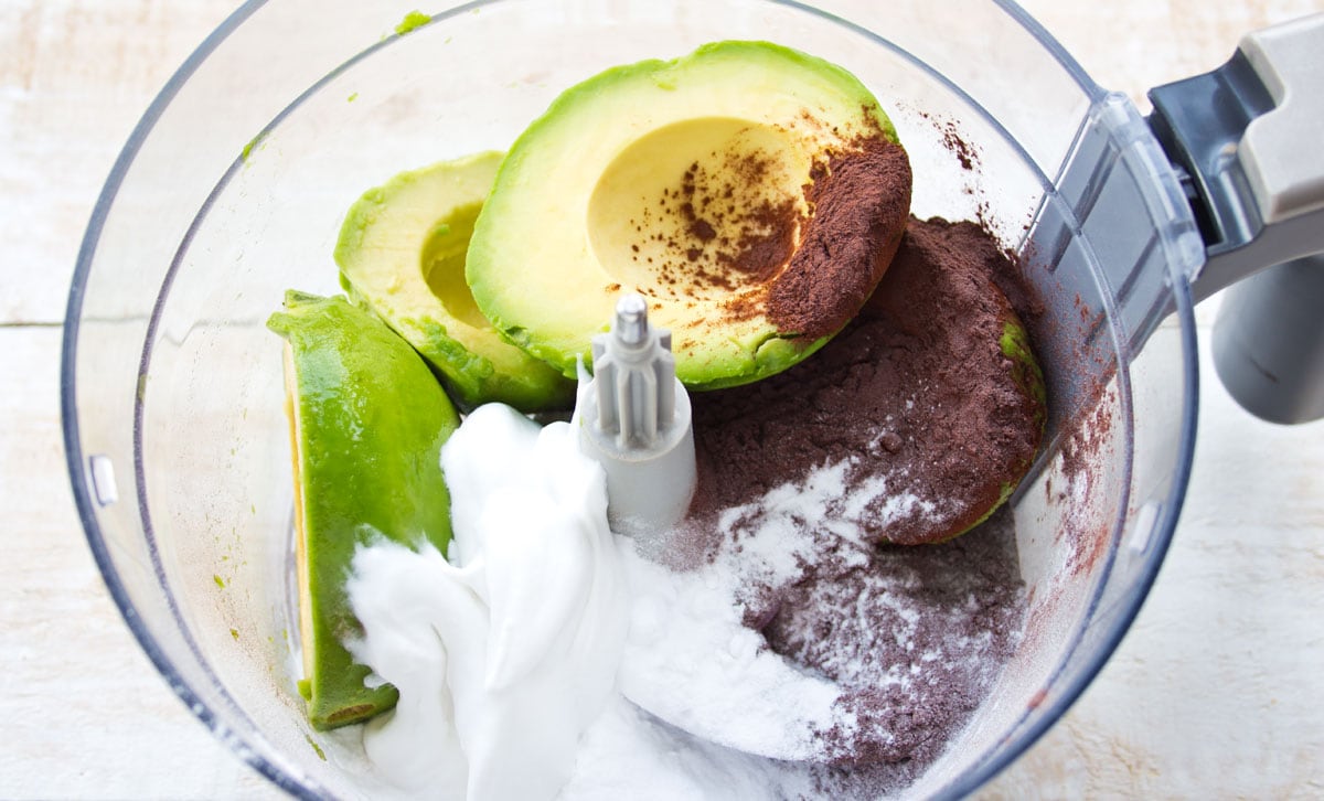Avocado, cocoa powder and sweetener in a food processor bowl.