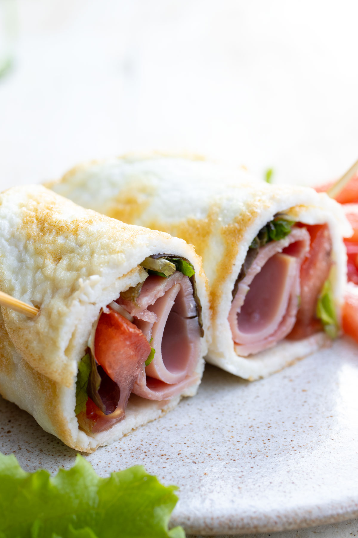 Two egg white wraps filled with ham and lettuce. 