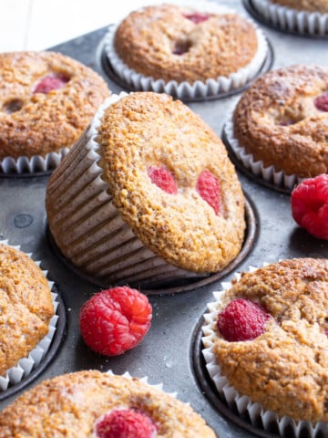 Flaxseed muffins with raspberries in a muffin tray.