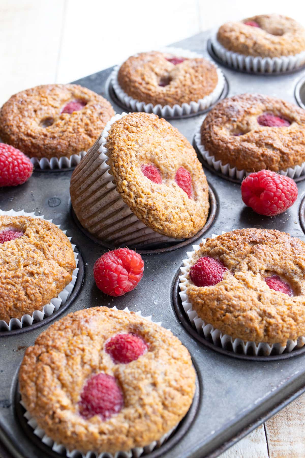 A muffin pan filled with raspberry studded muffins.