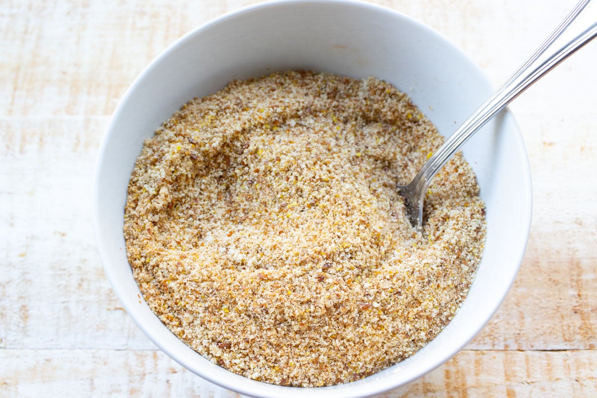 Ground flaxseed and other dry ingredients stirred together in a bowl.