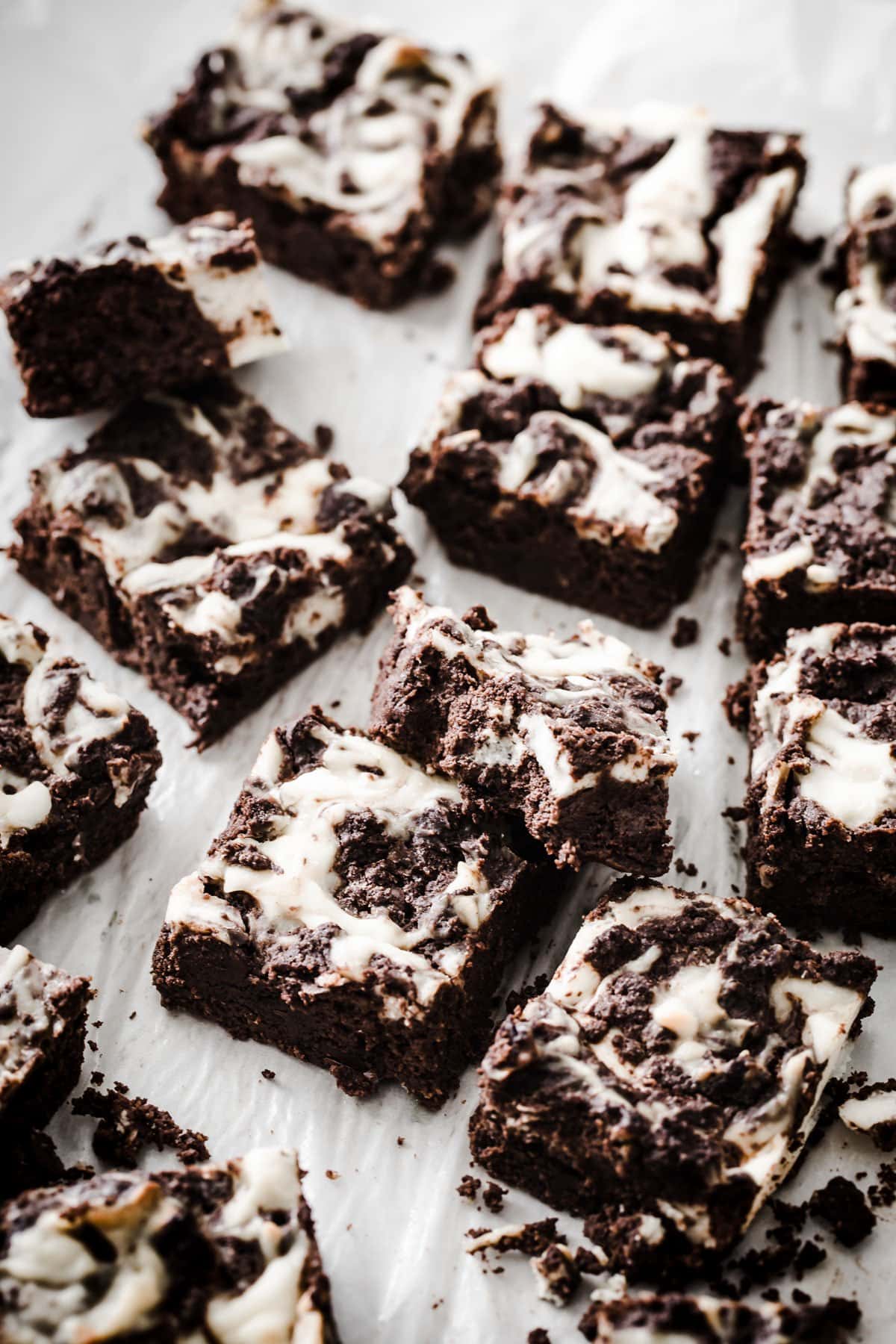 Brownie squares on parchment paper, one with a piece broken off.