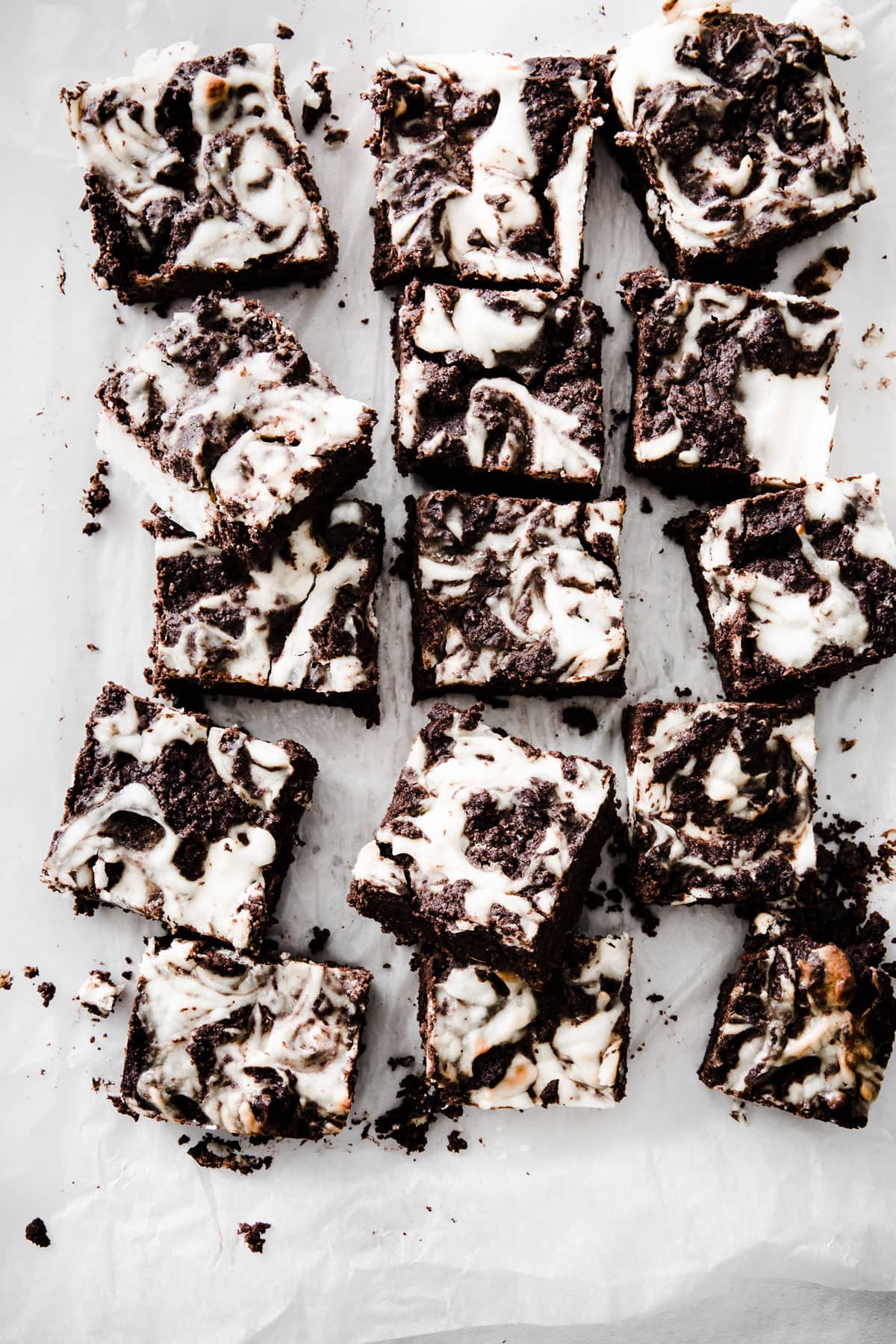 Cheesecake brownie squares on parchment paper.