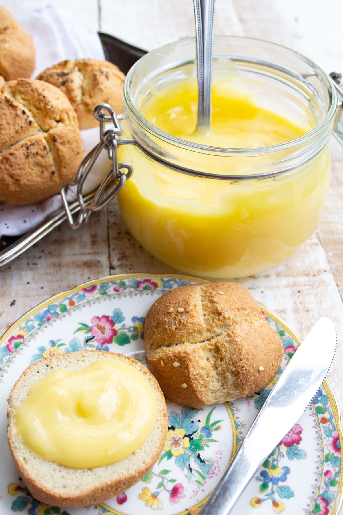 A roll topped with lemon curd on a plate.