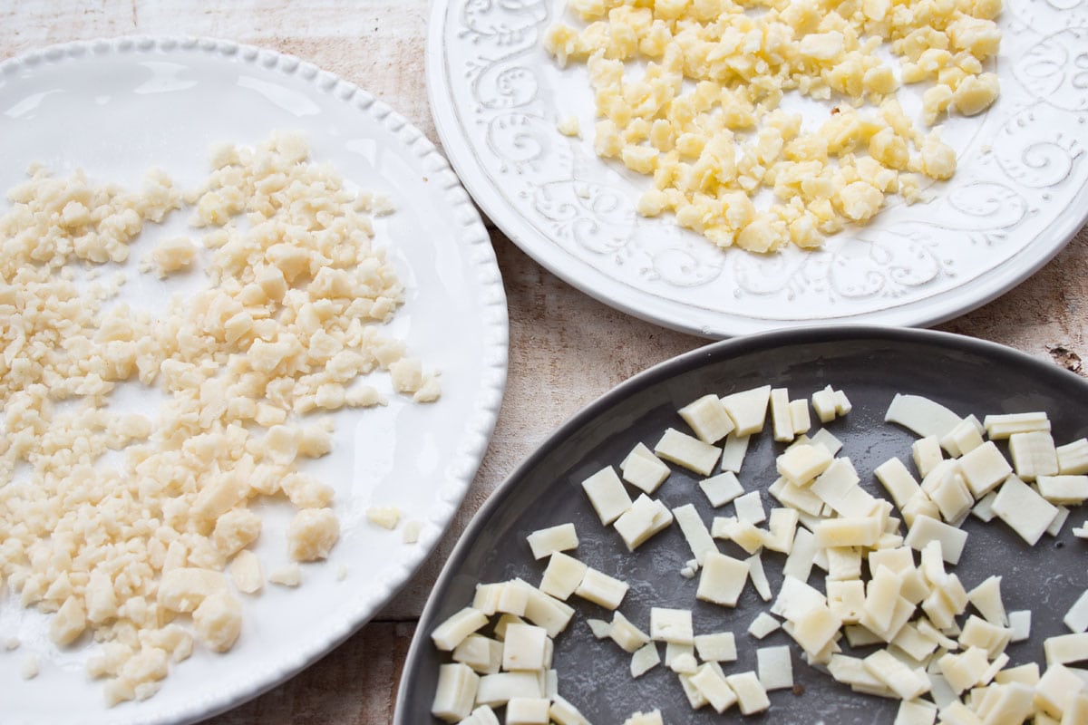 Crumbled and sliced cheese on 3 plates.