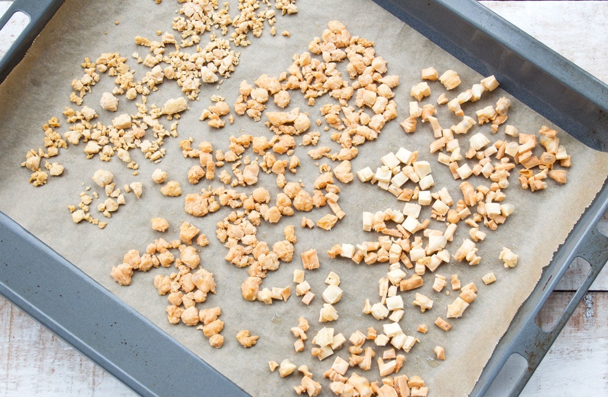 3 types of cheese puffs spread on a parchment paper lined baking tray.