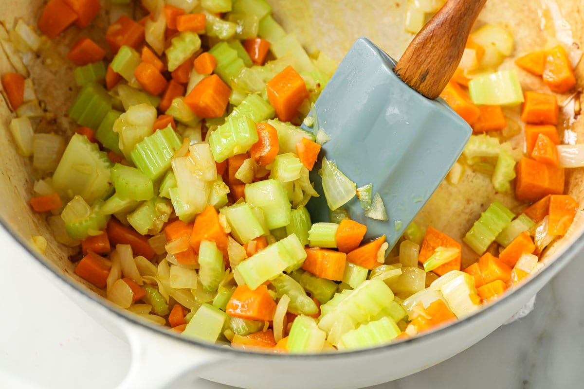 Chopped vegetables in a saucepan and a spatula.