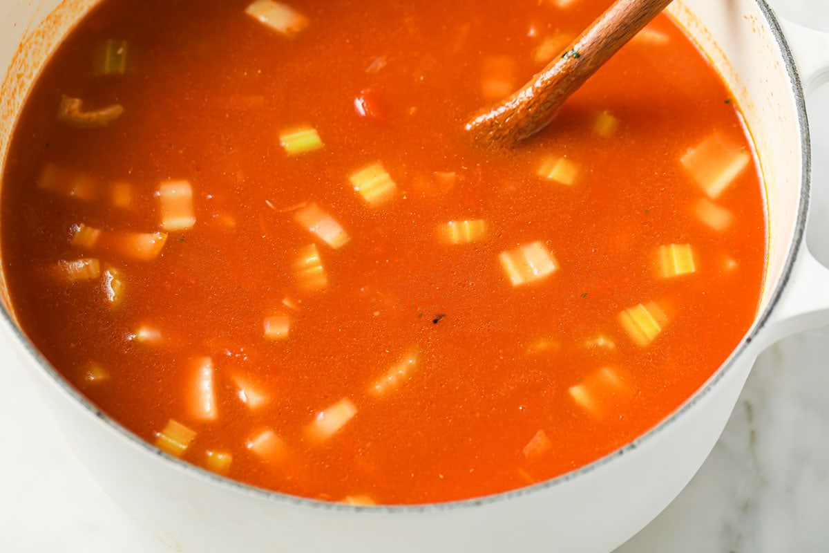 Tomato soup in a saucepan with a wooden spoon.