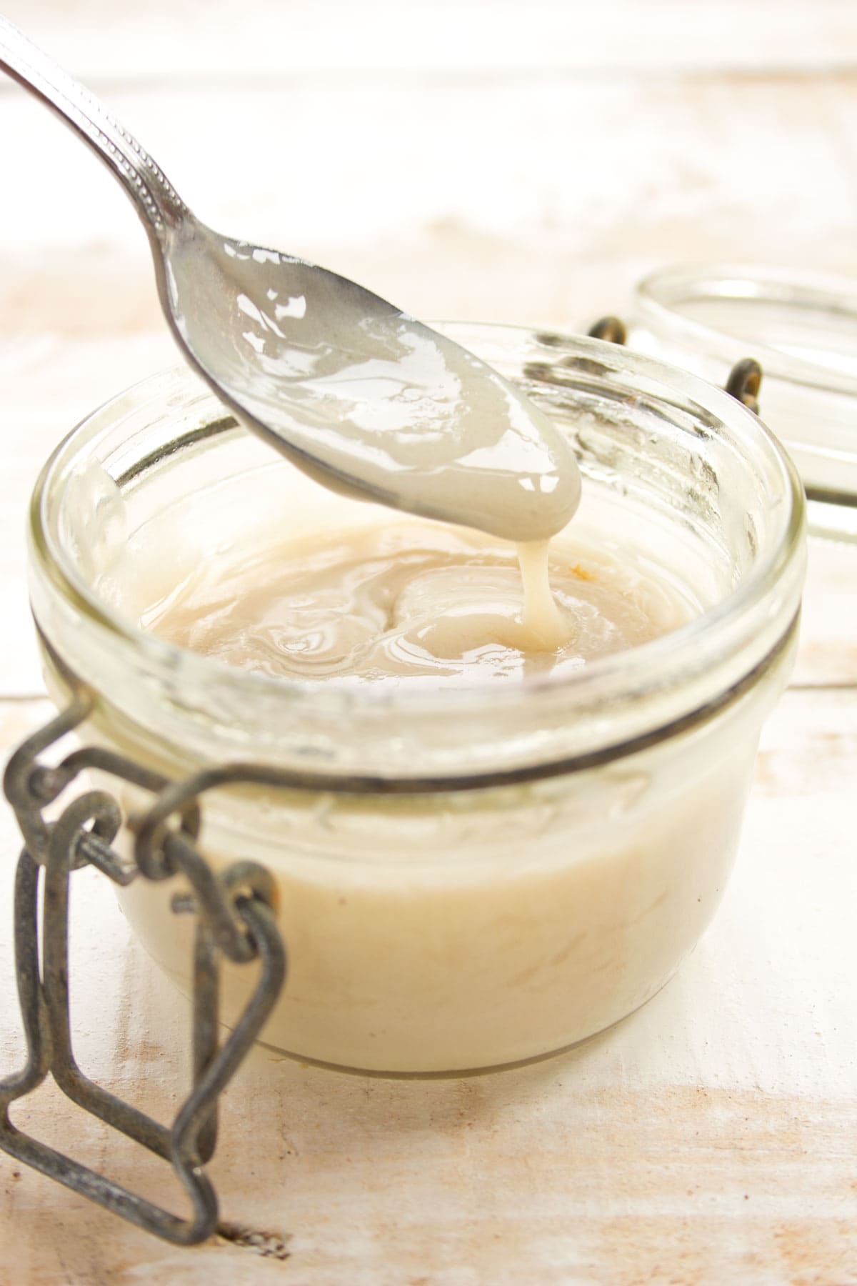 A glass jar with homemade condensed milk and a spoon.