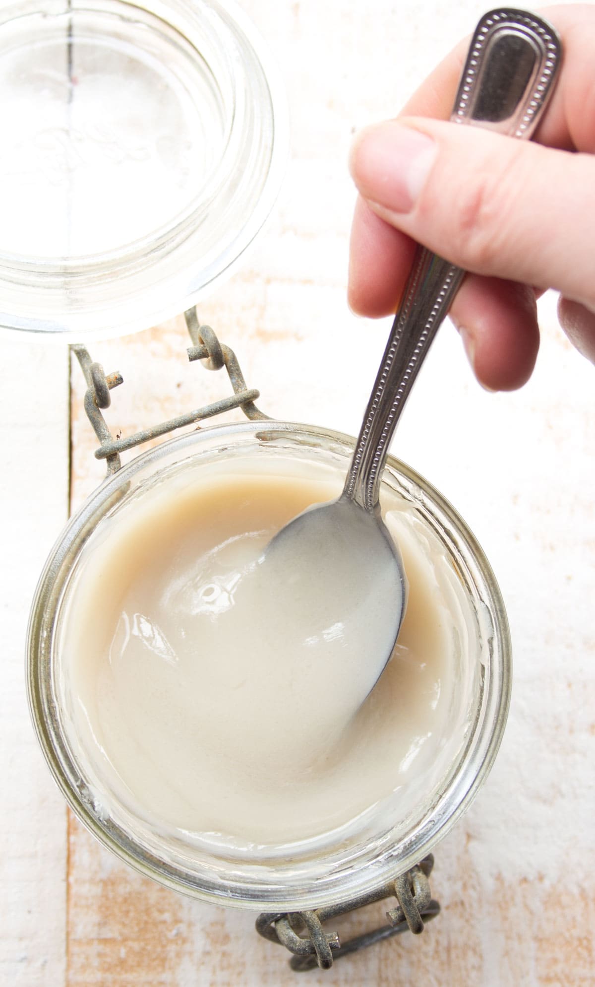 Sticking a spoon into a jar with condensed milk.