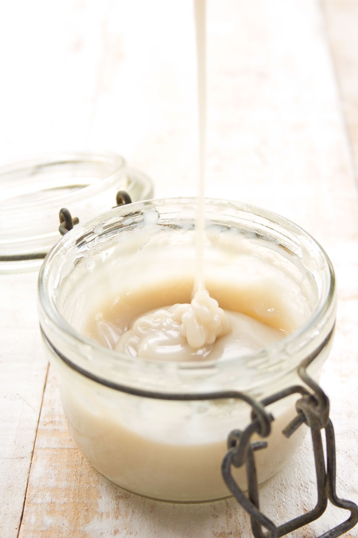 Pouring sugar-free condensed milk into a glass jar.