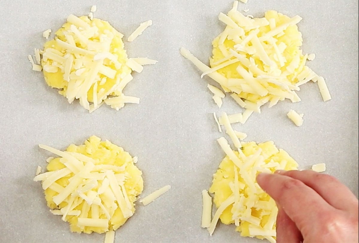 Topping the unbaked crackers with shredded cheese.