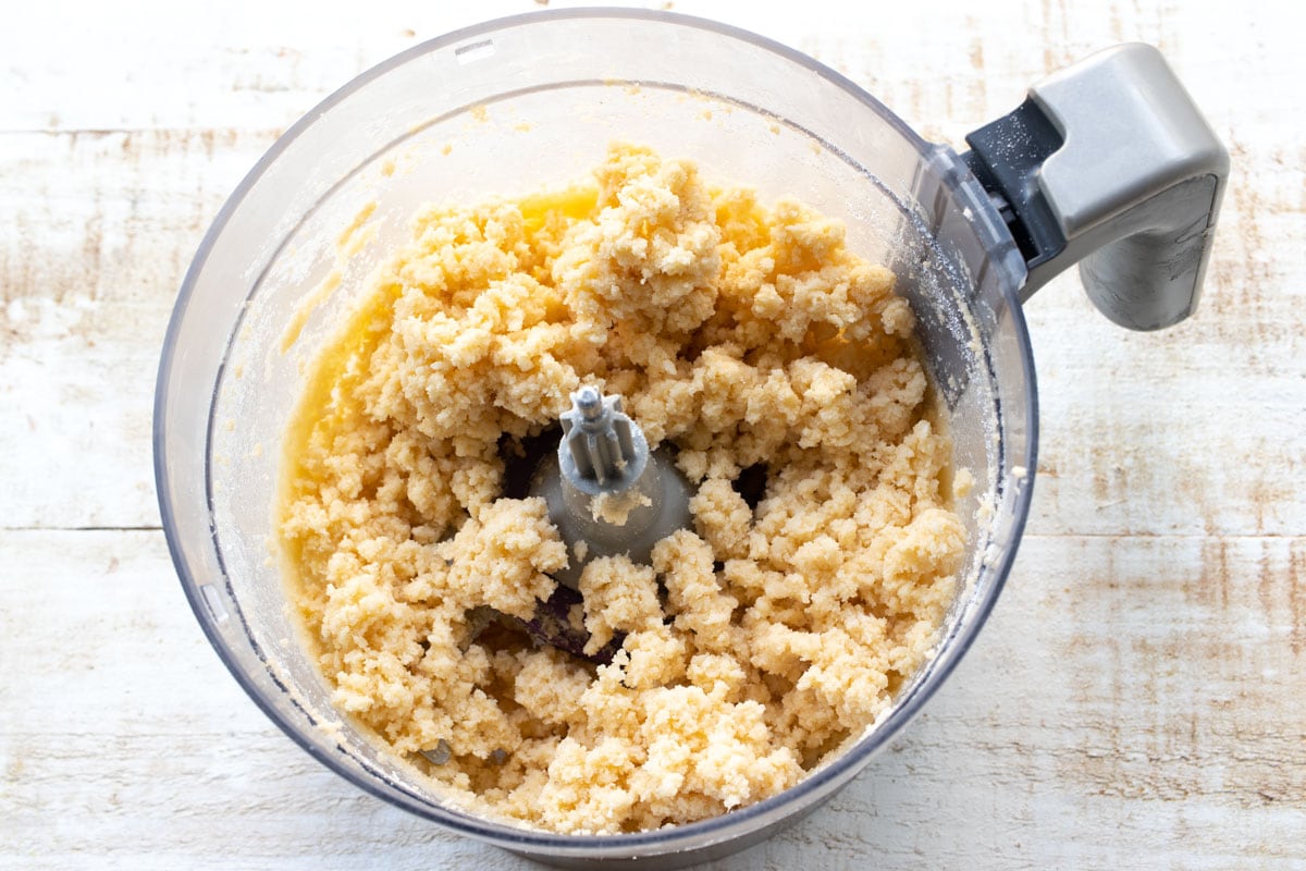 Crumbly dough in a food processor bowl.
