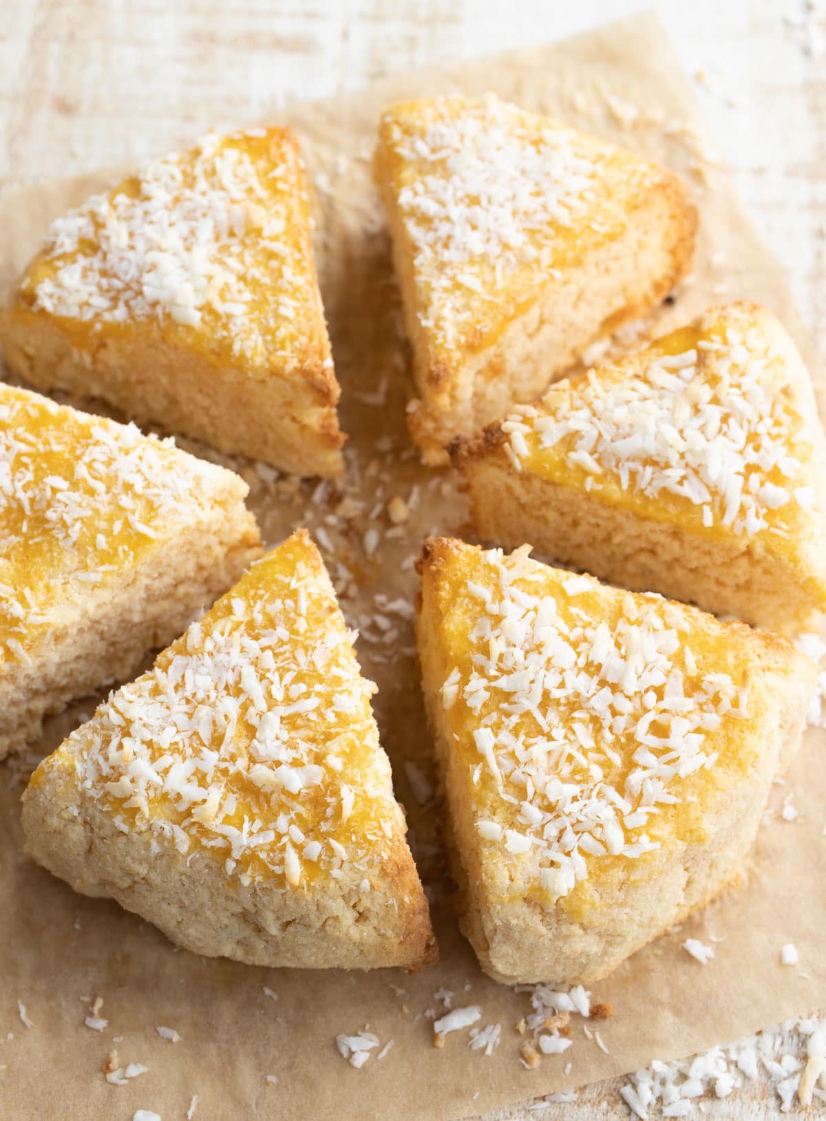 Coconut scones arranged in ta circle on parchment paper.