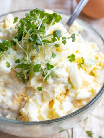 A bowl with egg salad and a spoon.