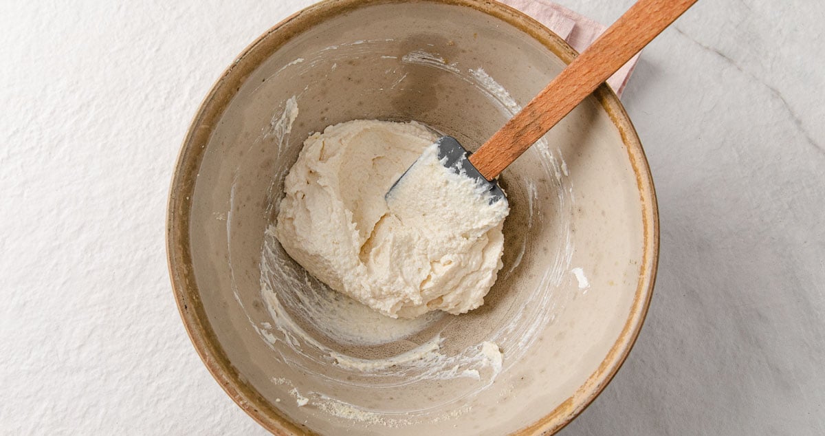 Cheesecake mix in a bowl with a spatula.