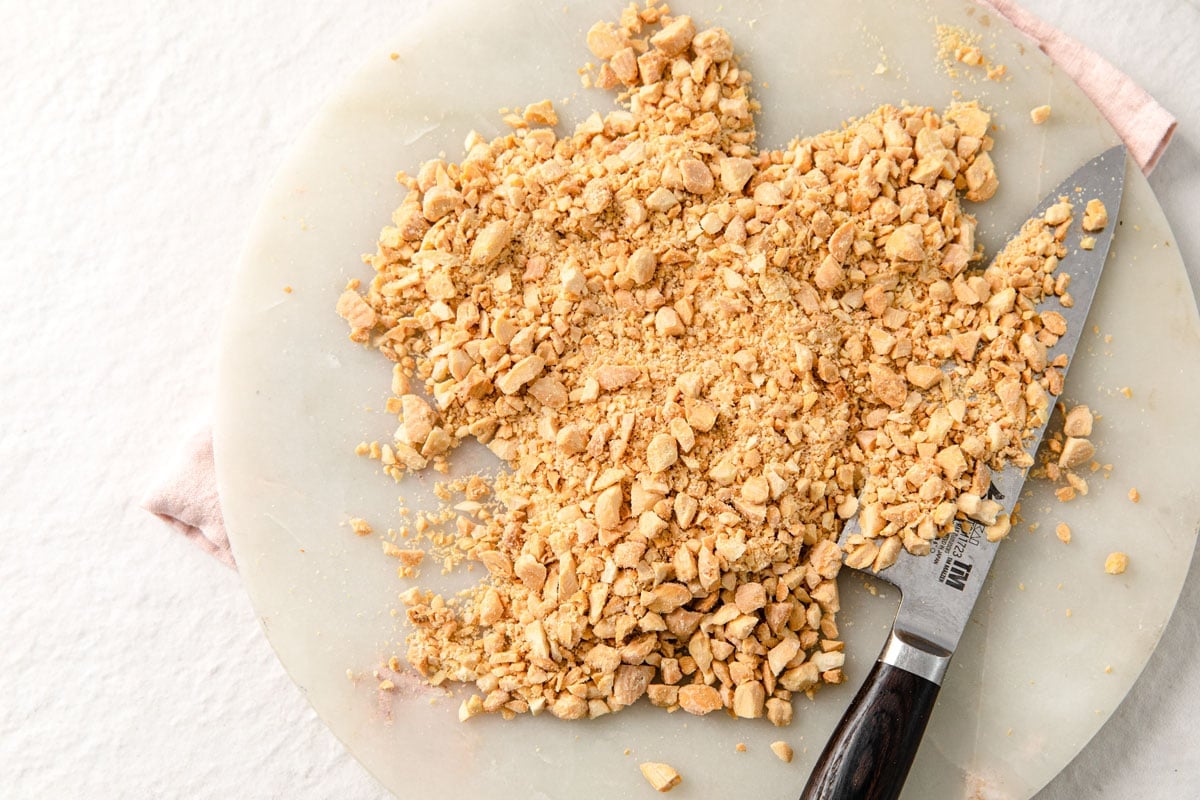 Chopped roasted almonds on a board and a knife.