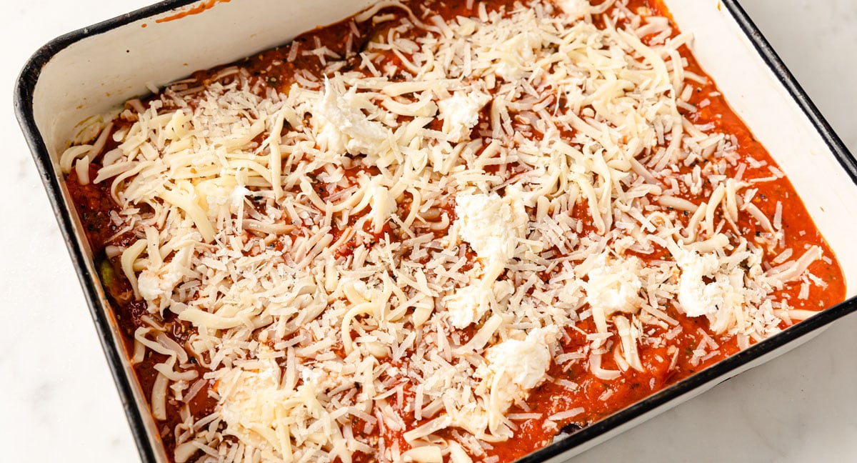The first layer of marinara sauce, eggplant and cheese in a casserole dish.