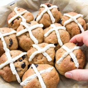 Hand picking up a hot cross bun.