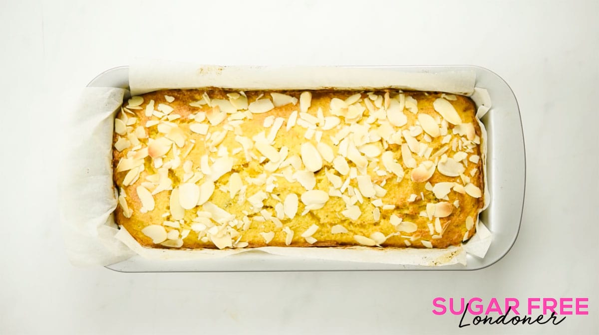 Baked orange cake topped with sliced almonds in a rectangular cake pan.