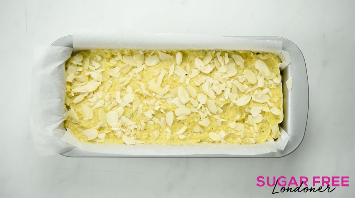 Orange cake batter in a rectangular pan lined with parchment paper.