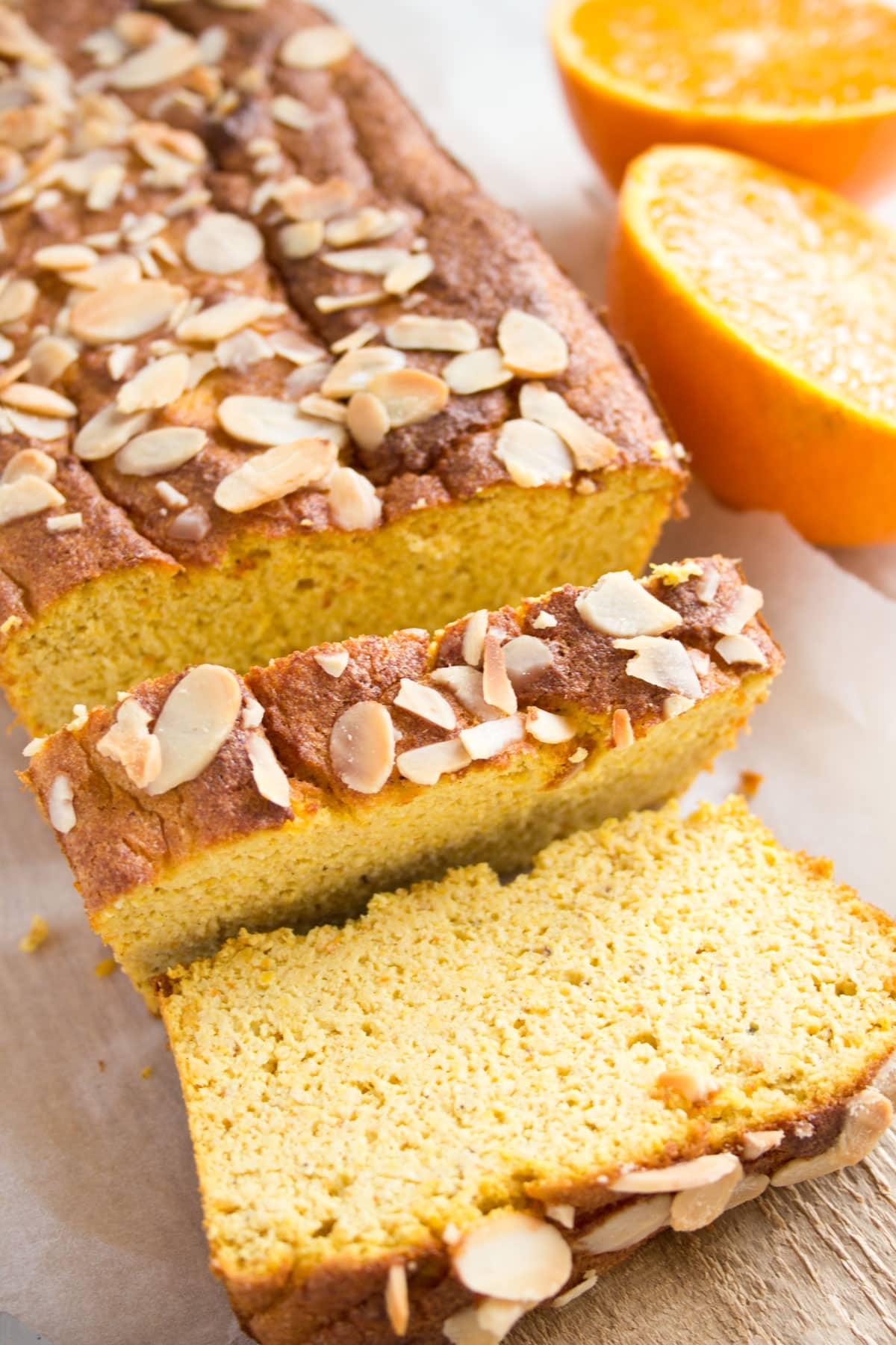 Orange almond loaf cake with 2 slices cut off.