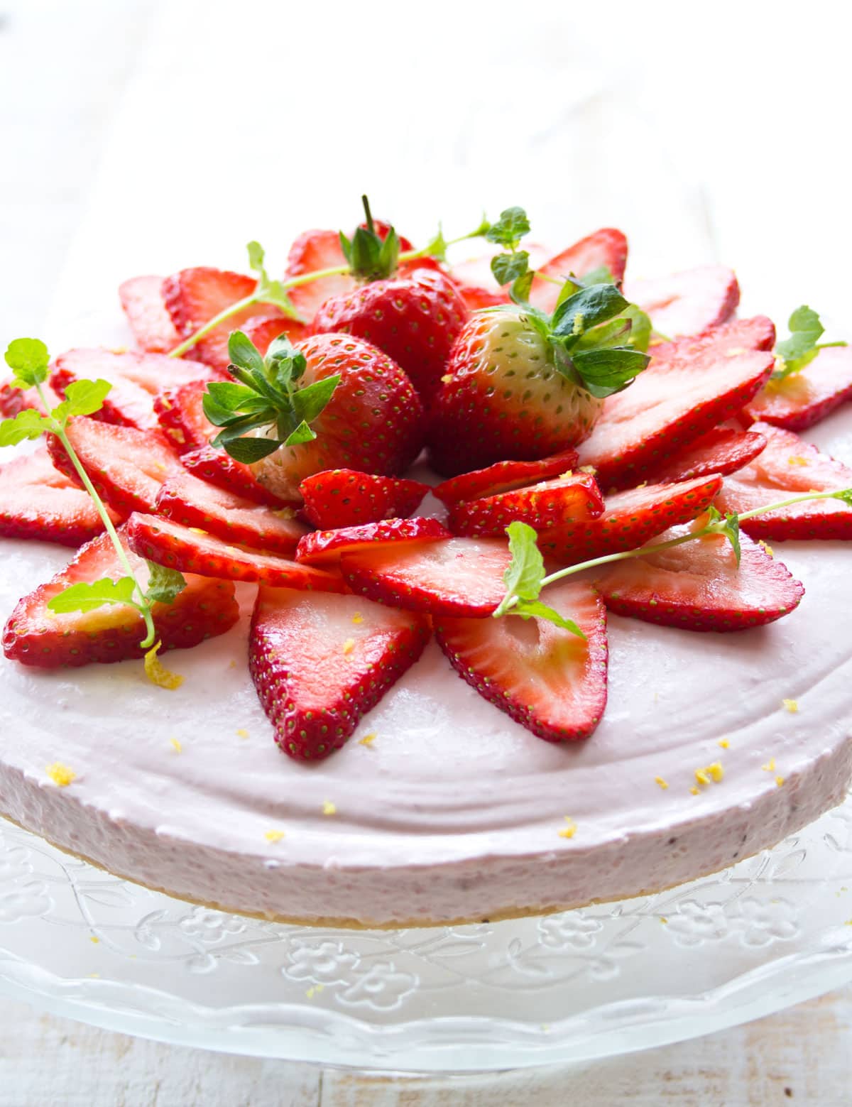 A strawberry cheesecake topped with sliced and whole strawberries.