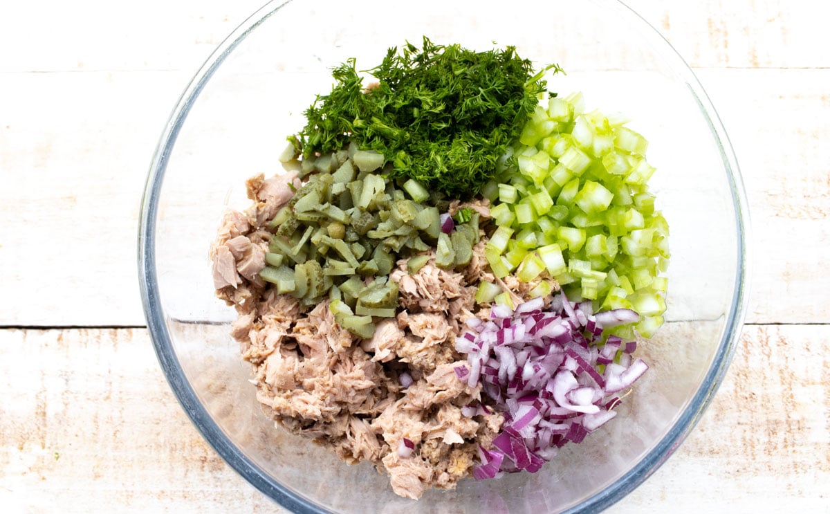 Tuna and chopped vegetables and herbs in a bowl.