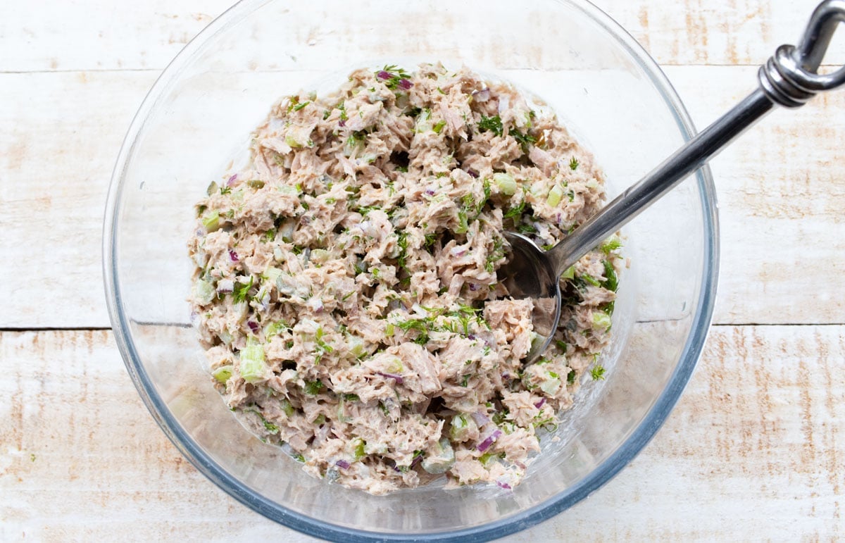 Tuna salad in a large mixing bowl and a spoon.