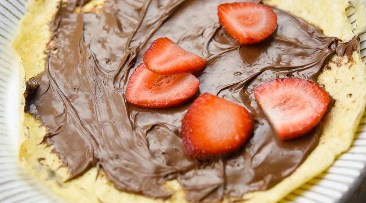 Nutella spread onto a crepe and topped with sliced raspberries.