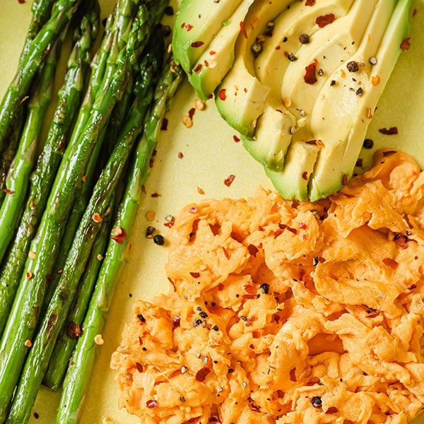 Scrambled egg with sliced avocado and asparagus.