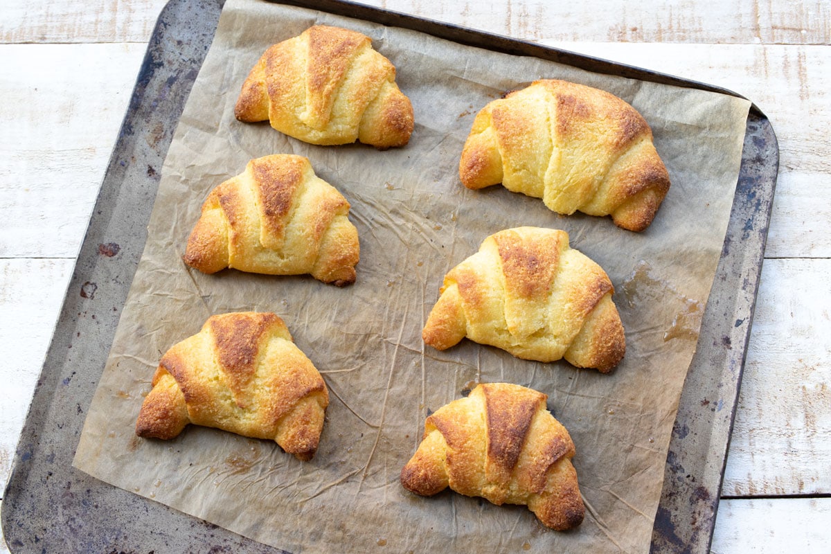 Baked croissants on a baking sheet lined with parchment paper. 