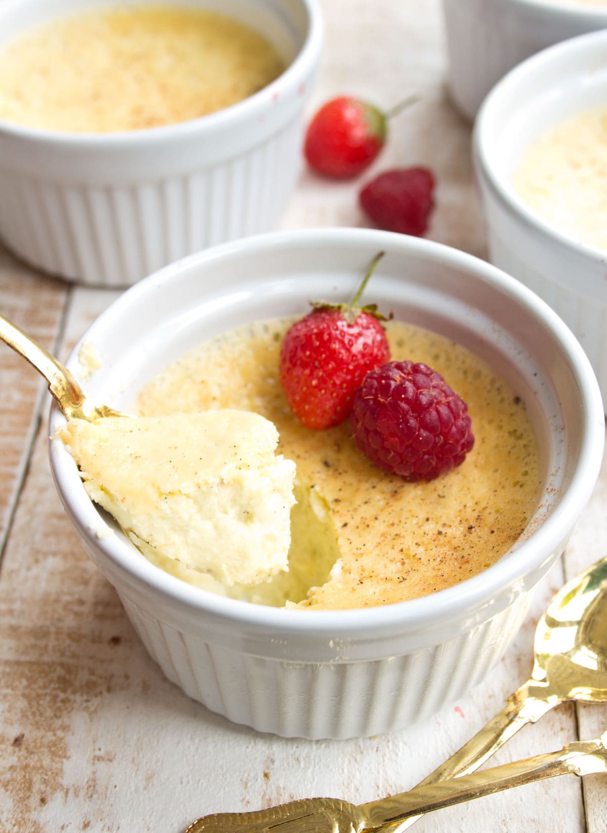 Custard decorated with berries and a golden spoon.