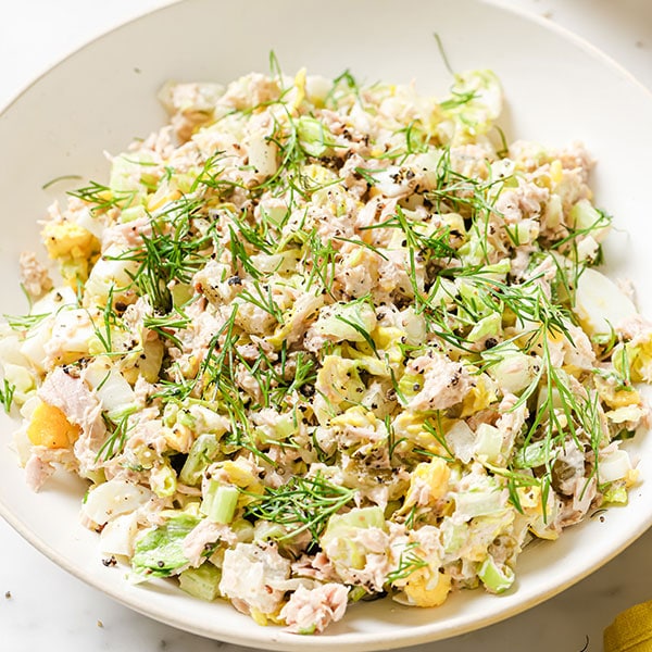 Chopped tuna and mayonnaise salad with fresh dill on a plate.