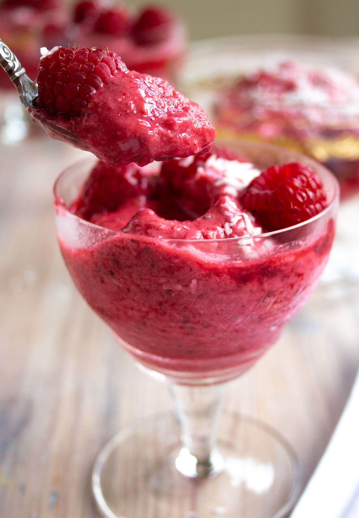 Taking a spoon with raspberry frozen yogurt out of a dessert bowl.