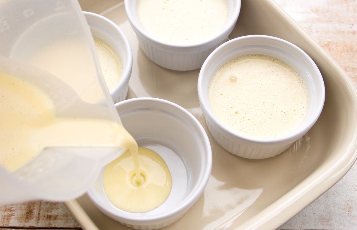 Pouring custard mixture into the ramekins.