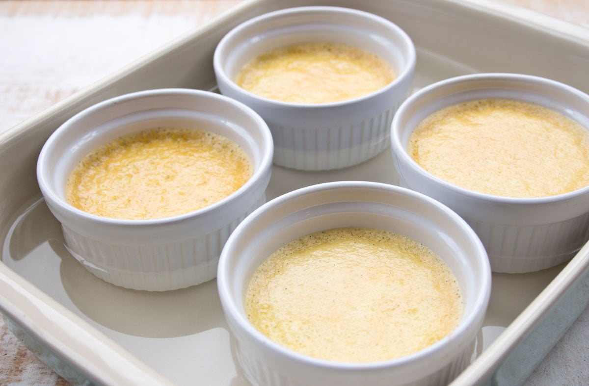 Baked custards in ramekins in a casserole dish half-filled with water.