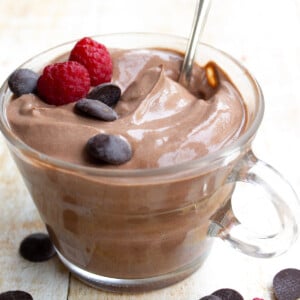 A glass cup with chocolate yogurt and a spoon.