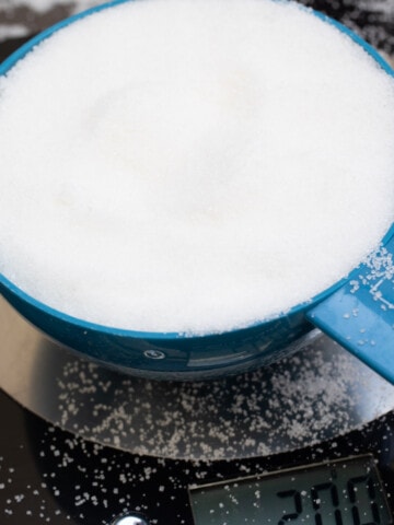A cup of sugar substitute on kitchen scales.