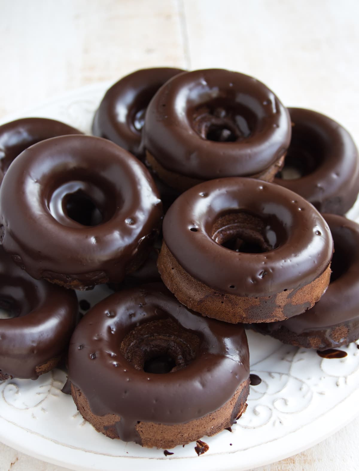 A plate stacked with chocolate glazed keto donuts.