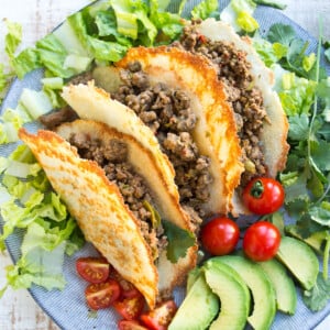 Three keto taco shells filled with beef and lettuce on a plate.