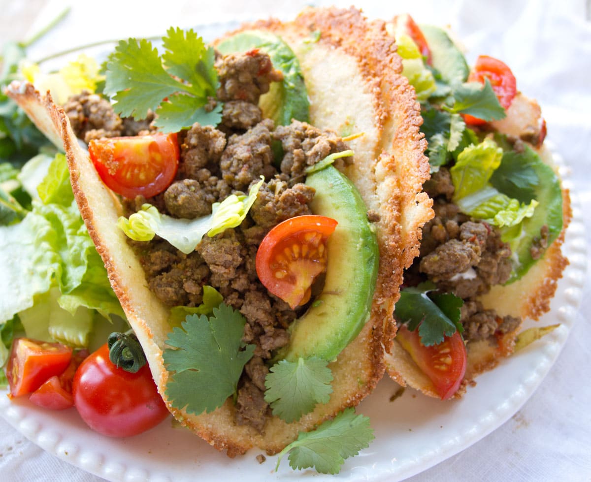 Filled taco shells on a plate.