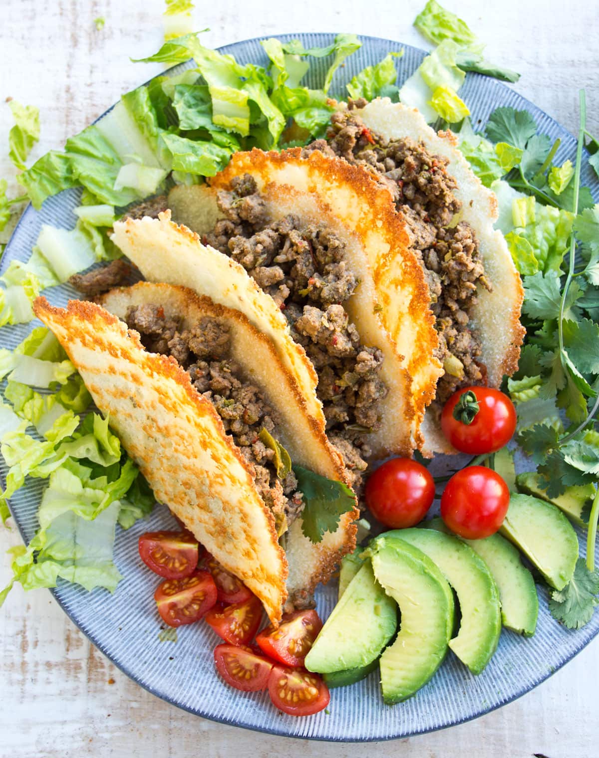 Taco shells filled with ground beef and lettuce on a plate.